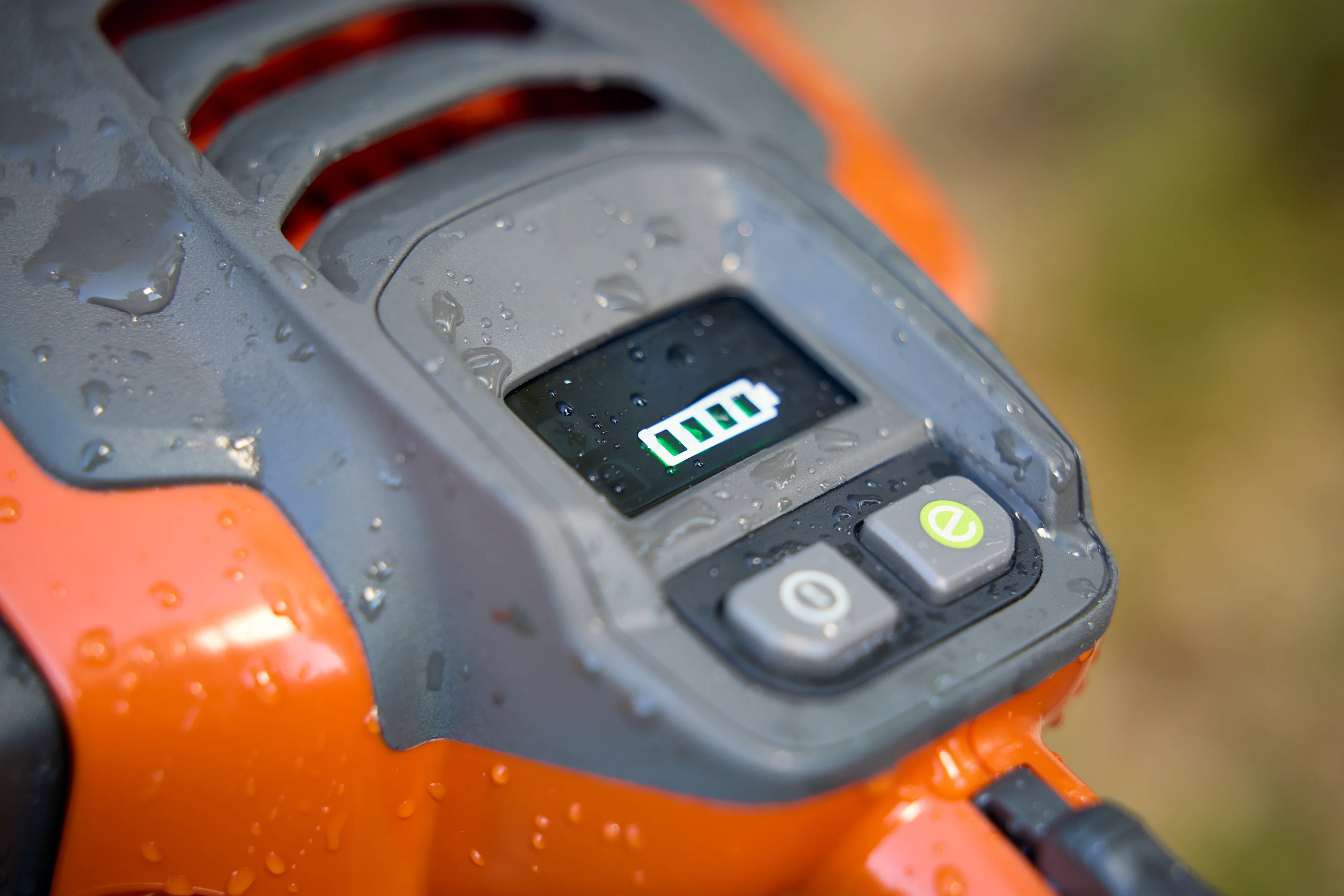 Nahaufnahme des regengeschützten Bedienfelds der Husqvarna 435i Akku-Motorsäge mit leuchtender Akku-Ladeanzeige und e-Taste.