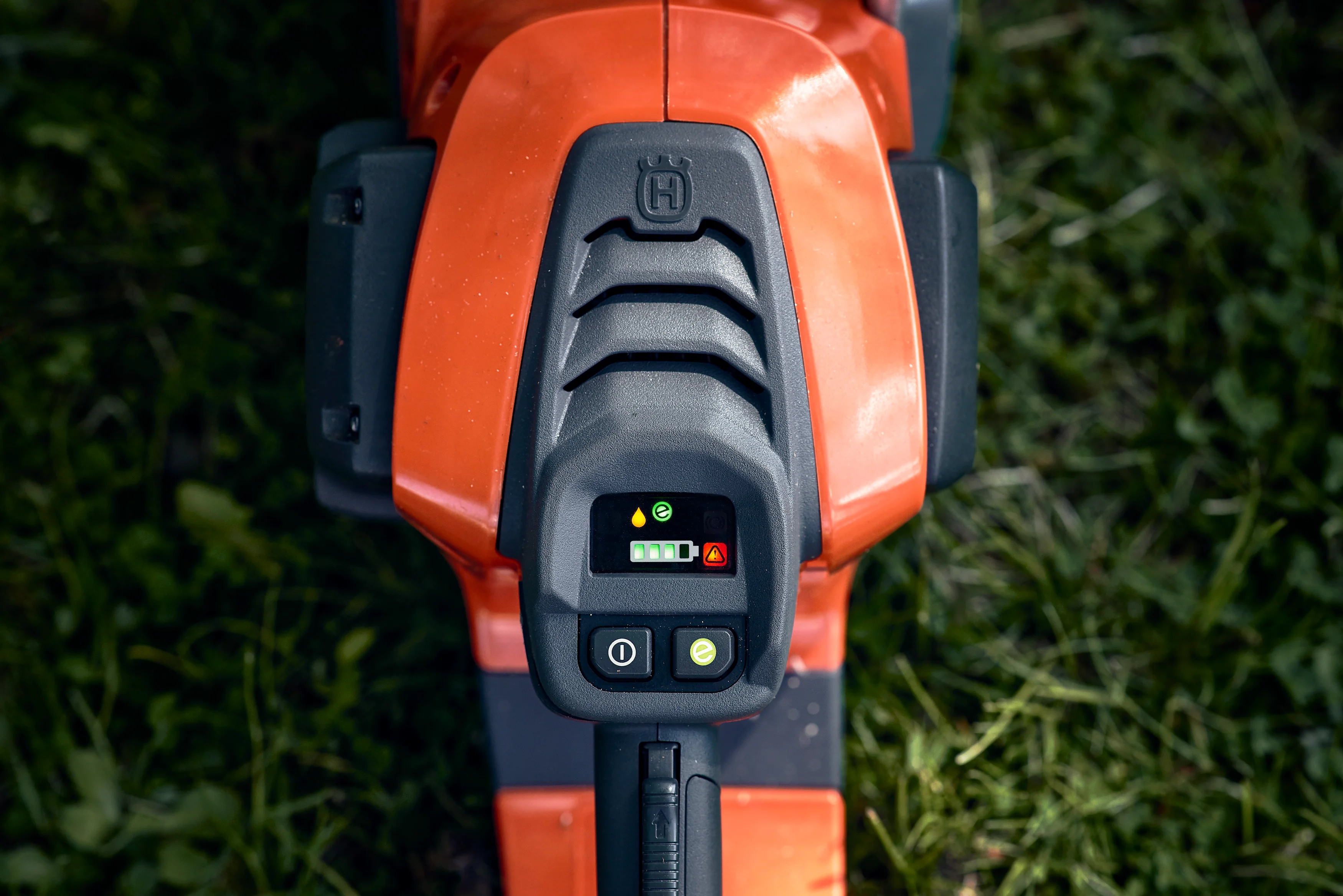 Draufsicht auf das digitale Bedienfeld einer Husqvarna Akku-Motorsäge mit Akku-Ladestandsanzeige, Ein-/Ausschalter und savE-Taste.