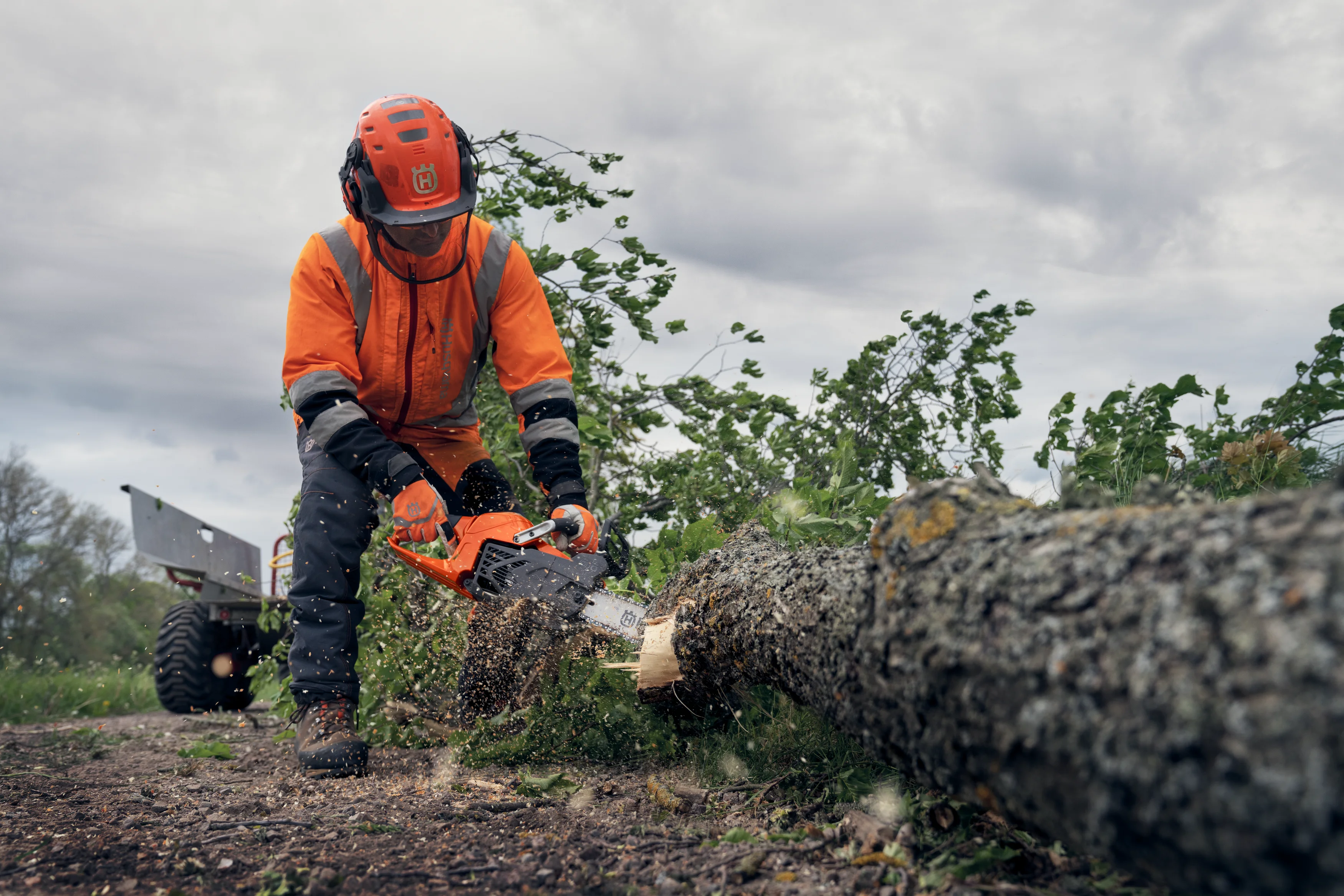 Forstarbeiter in Schutzkleidung sägt mit der Husqvarna 540 XP Mark III Benzin-Motorsäge an einem am Boden liegenden Baumstamm im Freien.